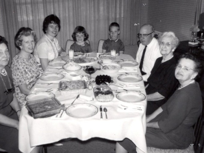 A group of people sitting around a table with food on it Description automatically generated with medium confidence